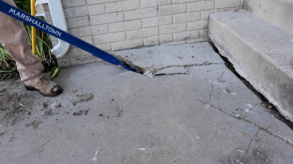 using a prybar to pry up old concrete